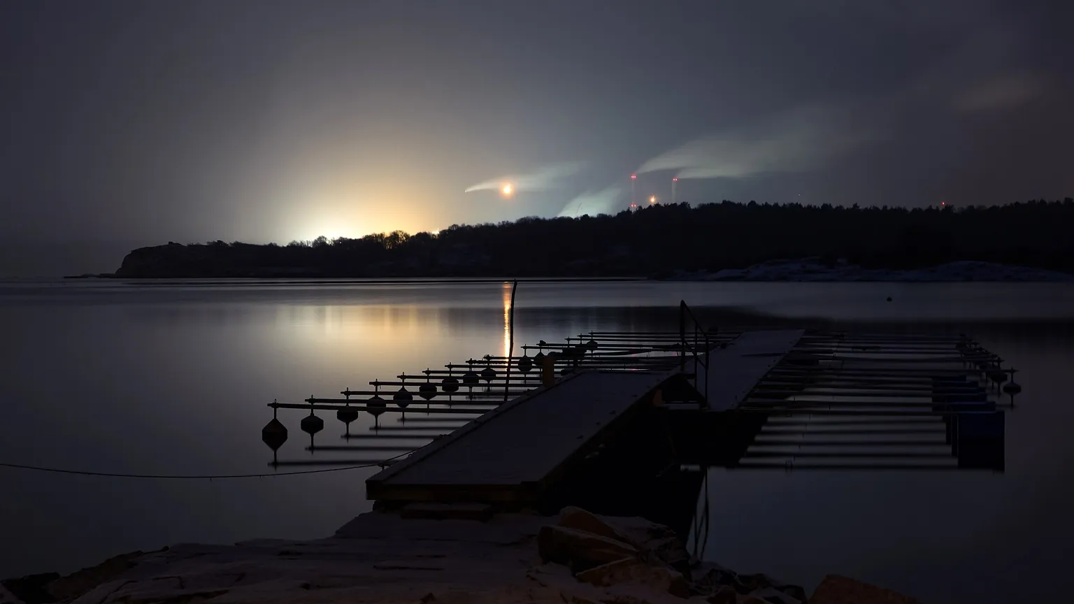 The glow of an oil refinery at night across a fjord